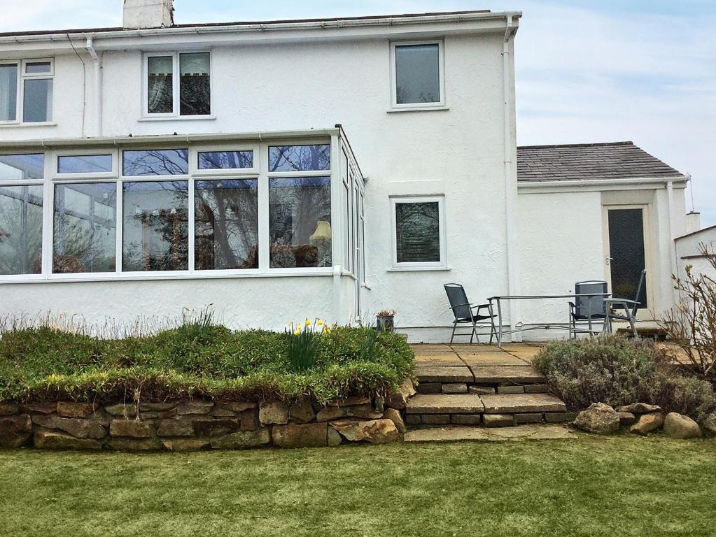 a white house with two chairs on a patio at Tyn Y Mur in Morfa Nefyn