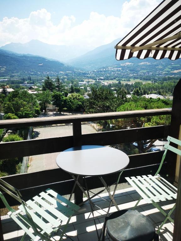 a table and chairs on a balcony with a view at Studio à 200 mètres la plage du Plan d'eau in Embrun