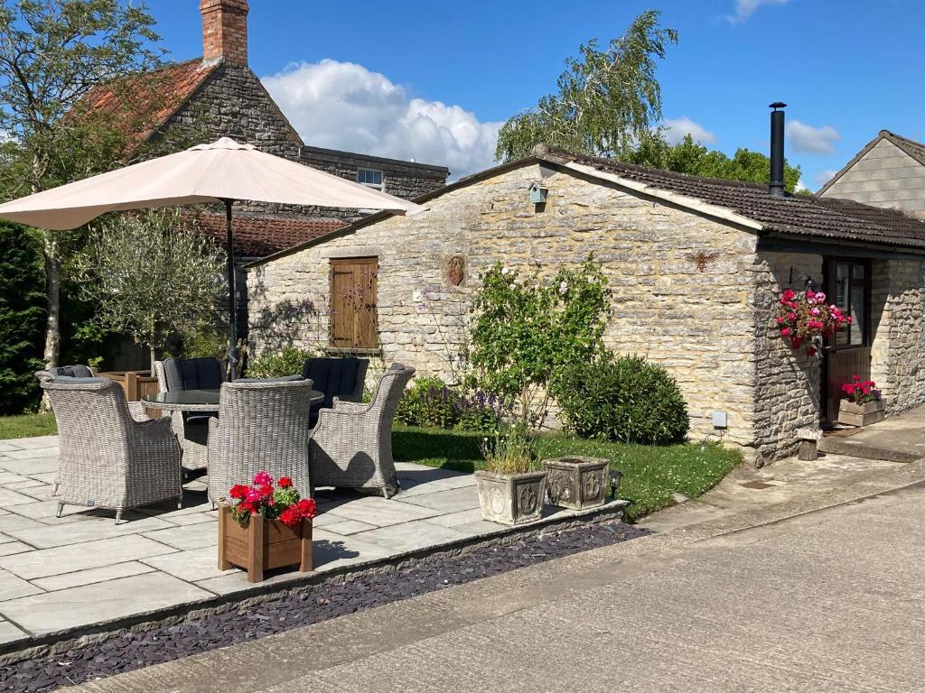 a patio with a table and chairs and an umbrella at Bee Cottage in East Lydford