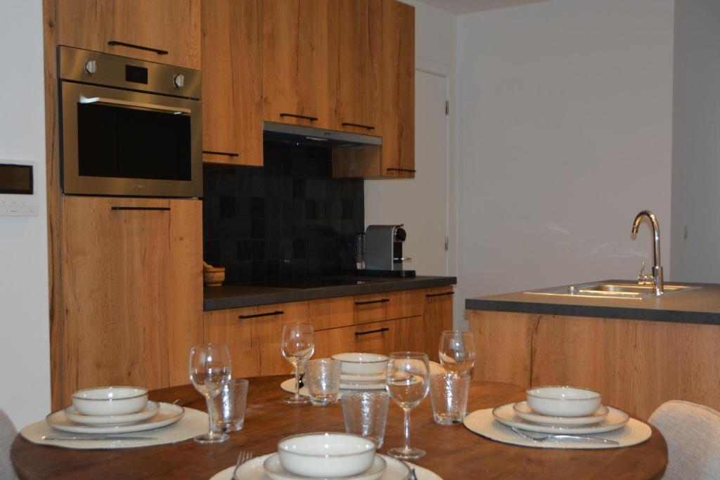 Una cocina con una mesa con platos y copas de vino. en Gezellig appartement Liva, en Blankenberge