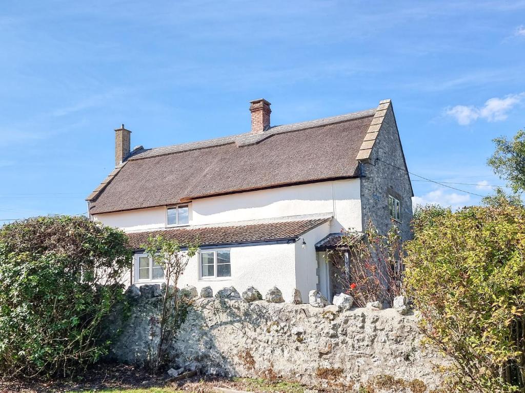 a small white house with a stone wall at The Moat House in Cudworth