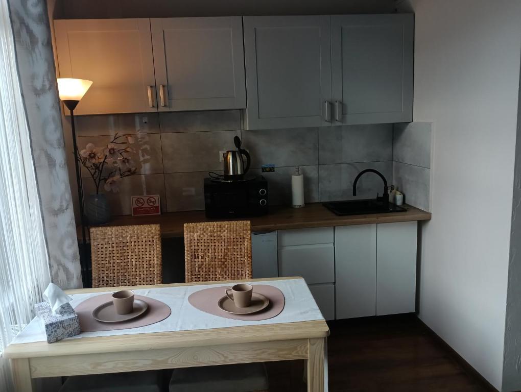 a kitchen with white cabinets and a table with two cups on it at Nocleg Pod Gubałówką in Zakopane