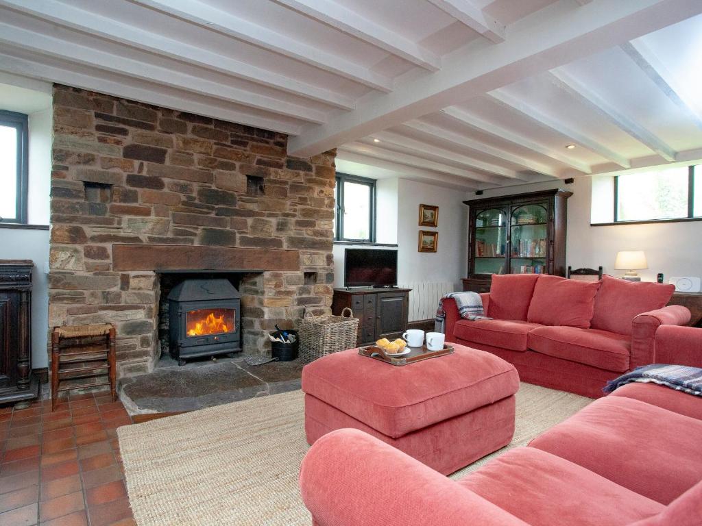 salon z czerwonymi kanapami i kominkiem w obiekcie Chapel Cottage w mieście Lydford