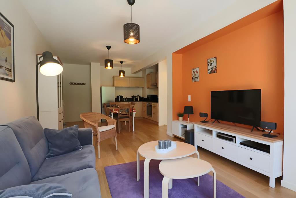 a living room with a couch and a flat screen tv at A5 - Résidence La Montille in Mont-Dore