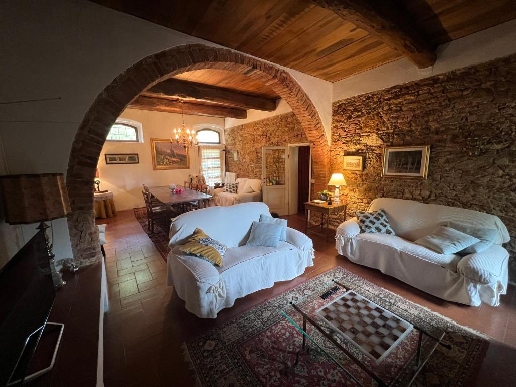 a living room with two white couches and a stone wall at La casa nel bosco in Lari