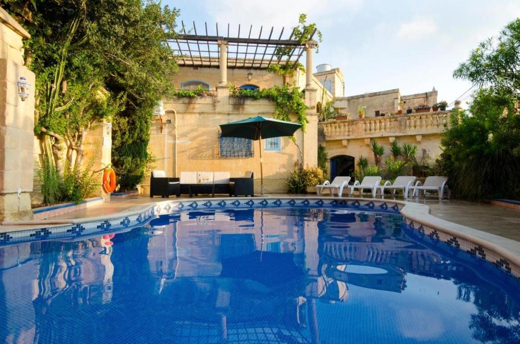 a large blue swimming pool in front of a building at Il-Wileg B&B in Qala