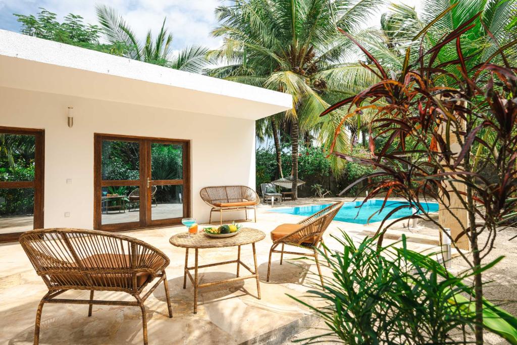 a patio with chairs and a table next to a pool at White Paradise Zanzibar in Pongwe
