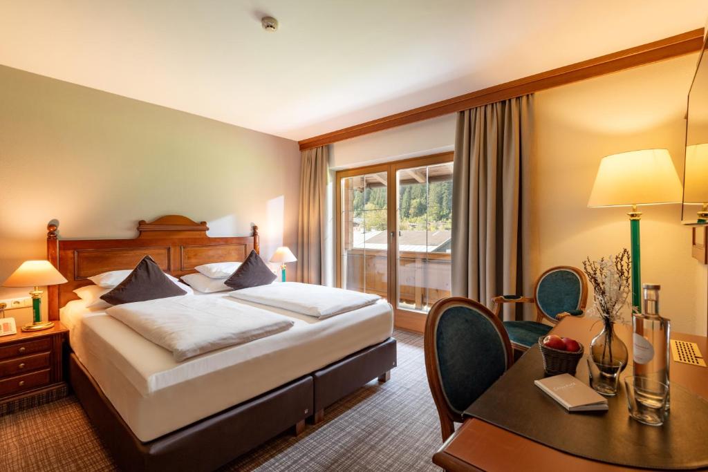 a hotel room with a bed and a table and a desk at Hotel Elisabeth, 4 Sterne Superior in Kirchberg in Tirol