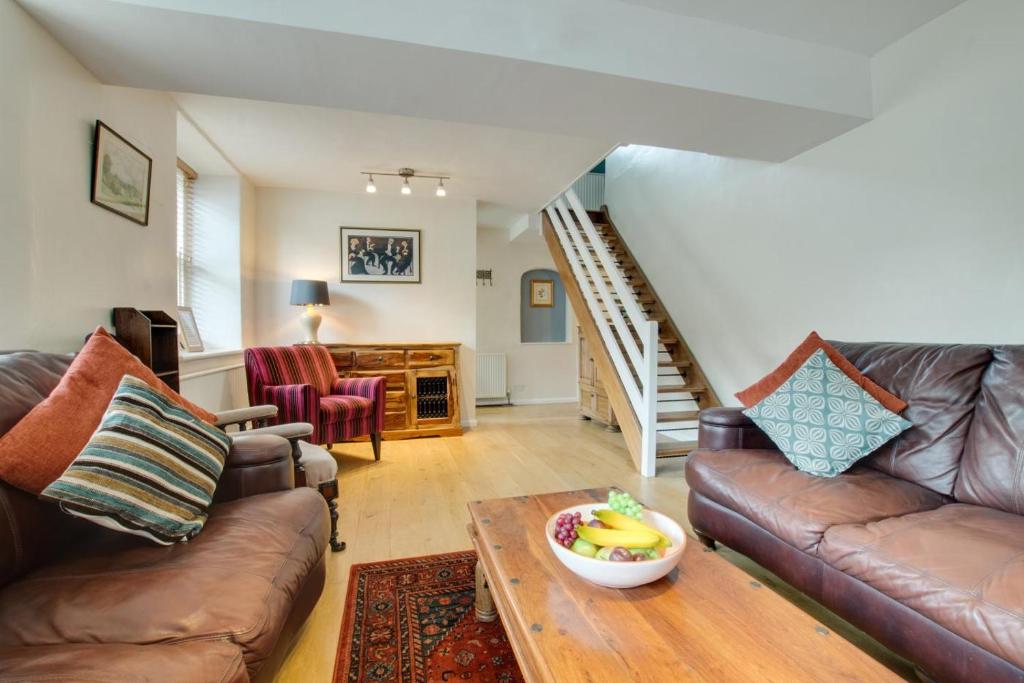 a living room with couches and a table with a bowl of fruit on top at Jaret House in Tideswell