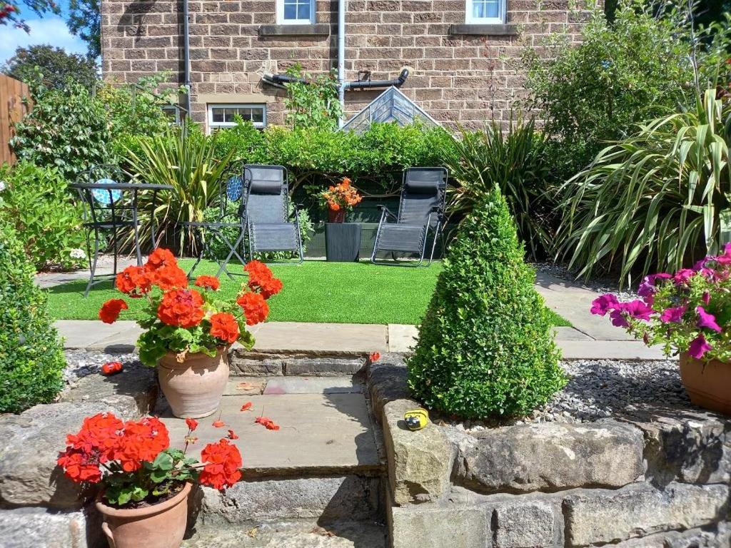 un jardin avec des fleurs et des chaises ainsi qu'un bâtiment dans l'établissement Araglen, à Matlock