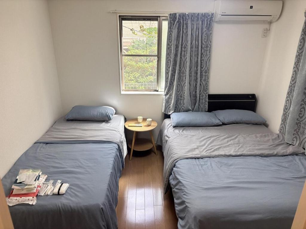 two beds in a room with a table and a window at Ikebukuro池袋1stop-2min-Kitaikebukuro北池袋walk3min in Tokyo