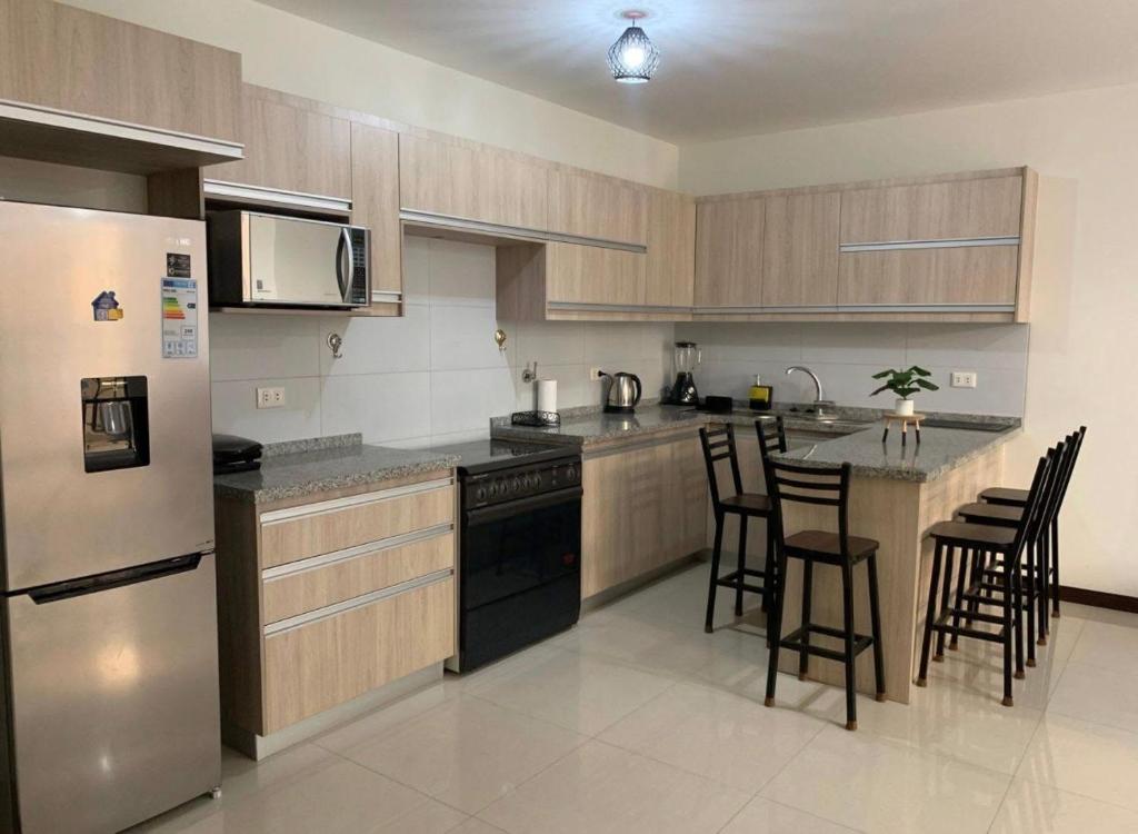 クスコにあるLos Tambos Apartmentのキッチン(ステンレス製の電化製品、木製キャビネット付)