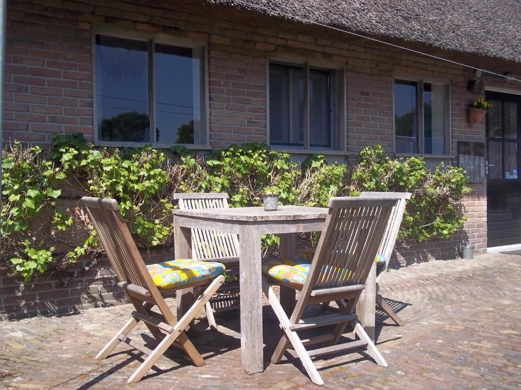 una mesa de madera y 2 sillas junto a un edificio en B&B Slaoperij en Orvelte