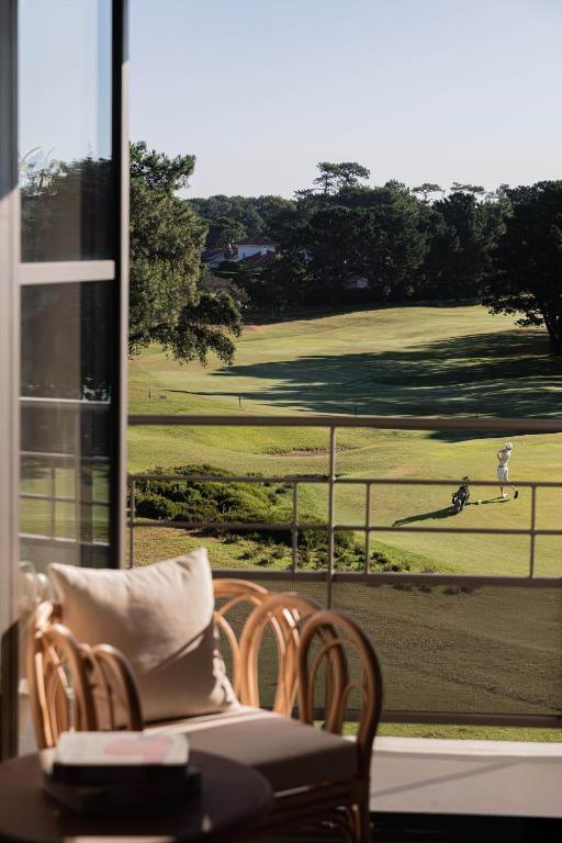 a table and chairs with a view of a golf course at Hôtel Maison Chiberta in Anglet