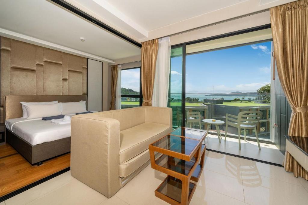 une chambre avec un lit et une chaise et un balcon dans l'établissement Panora sea view -modern facilities walk to beach, à Surin Beach