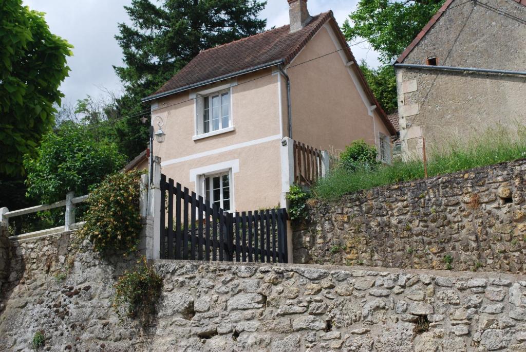 a house with a fence and a stone wall at La caburoche de Charlemagne in Civray-de-Touraine