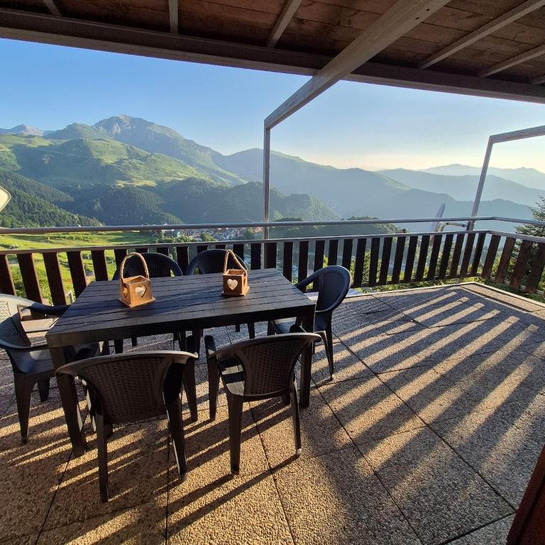 a wooden table and chairs on a deck with mountains at Le Terrazze del Sagittario - Top View - PVT Parking in Prato Nevoso