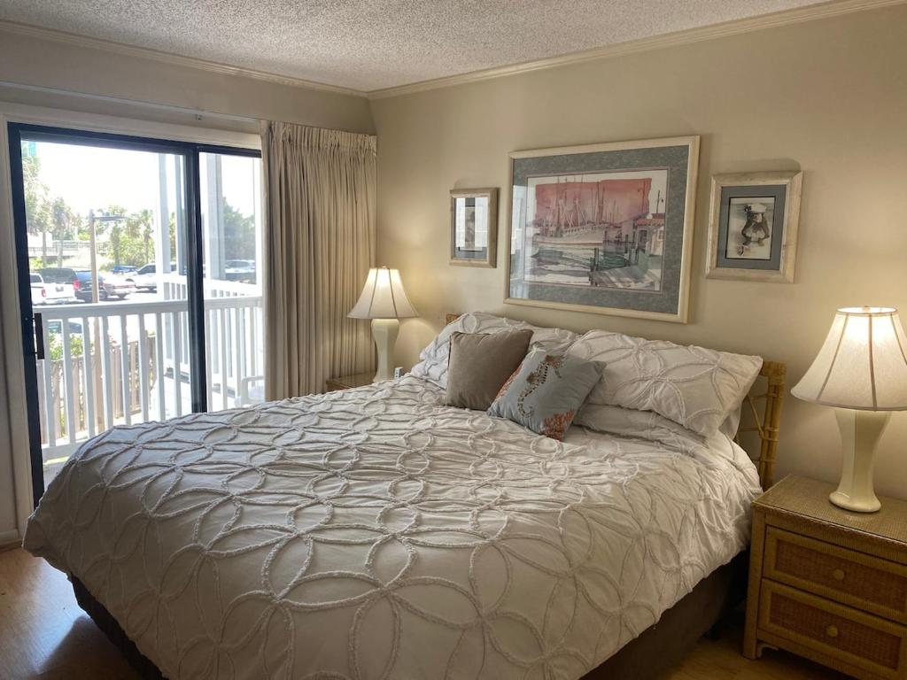 a bedroom with a large bed and a balcony at Seasons In The Sun in North Myrtle Beach
