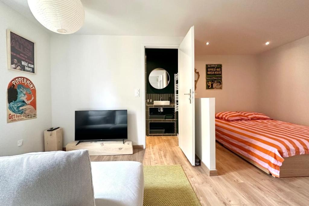 Un dormitorio con una cama y un televisor de pantalla plana. en Il Piccolo - Cosy emplacement de rêve, en Bandol