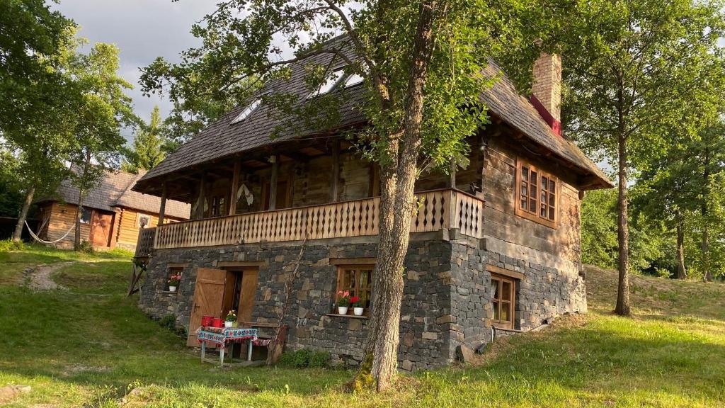 an old stone house with a tree in front of it at Poiana Creasta Cocoșului-Casa Mac in Breb