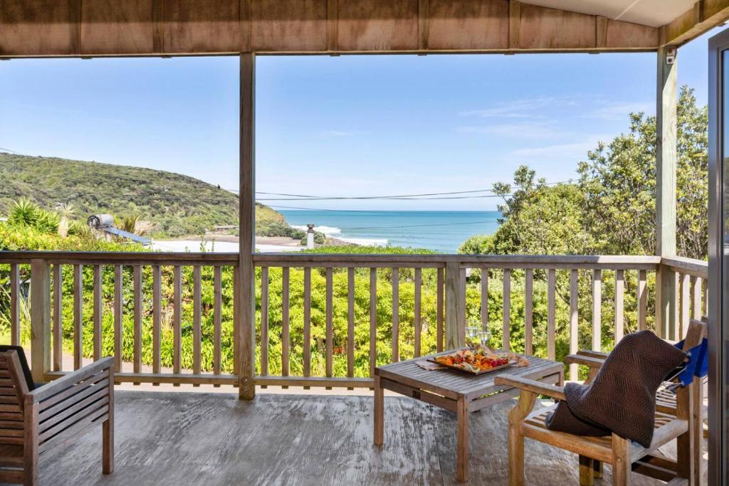 a porch with a table and chairs and a view of the ocean at HORIZON SURF LODGE plus private spa in Raglan
