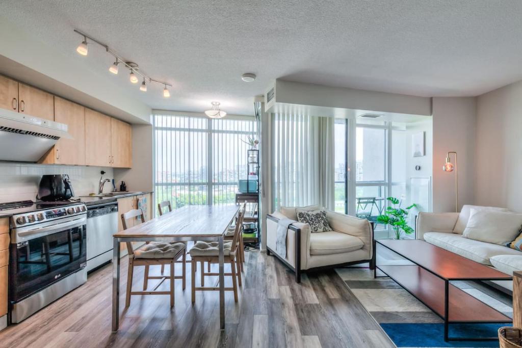 a kitchen and living room with a table and a couch at Chic 1BR plus Den Condo with Fast WiFi and Free Parking in Toronto
