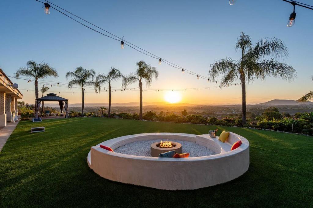 a fire pit in a yard with a sunset in the background at The Grape Escape Panoramic Views In Wine Country in Temecula