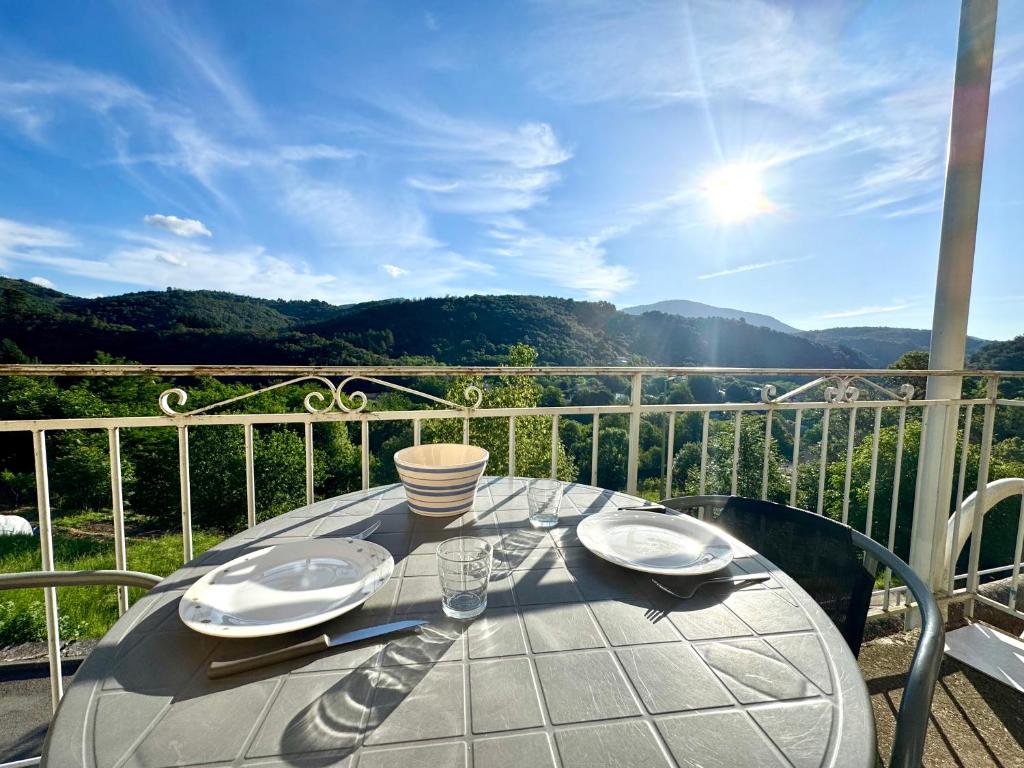 a table on a balcony with a view of the mountains at La Vallée Appartement 31 - Thermes Neyras les Bains in Meyras