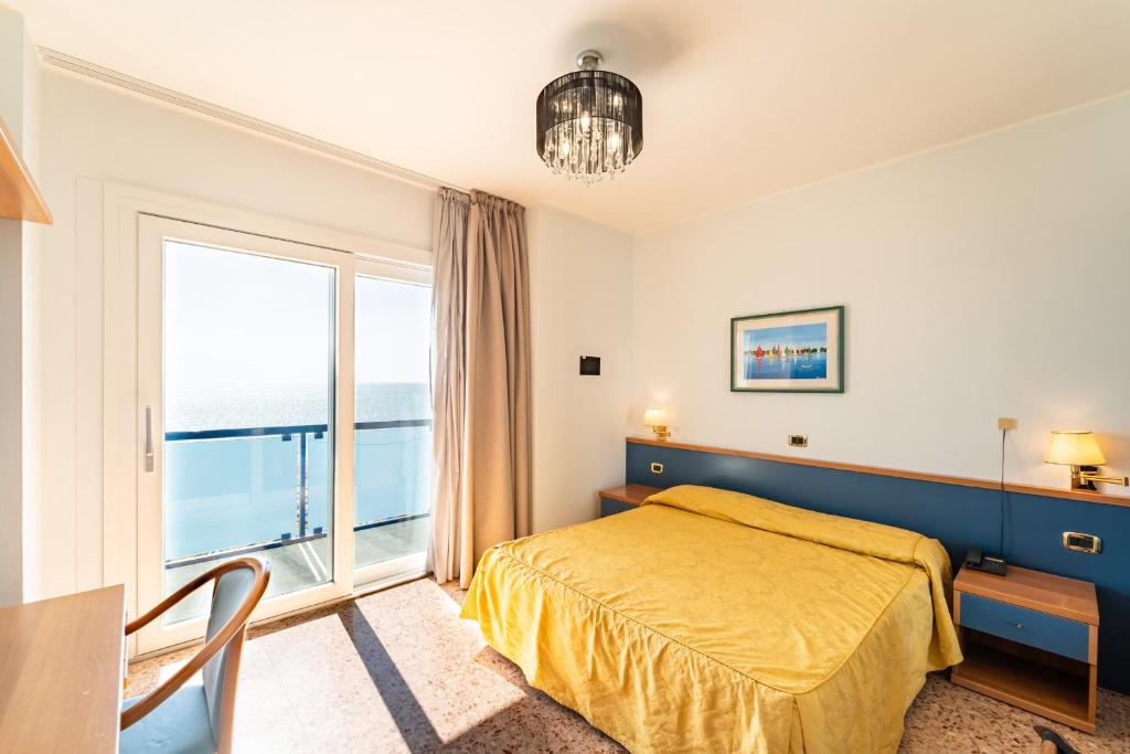 a bedroom with a bed and a large window at Hotel Souvenir in Lido di Jesolo