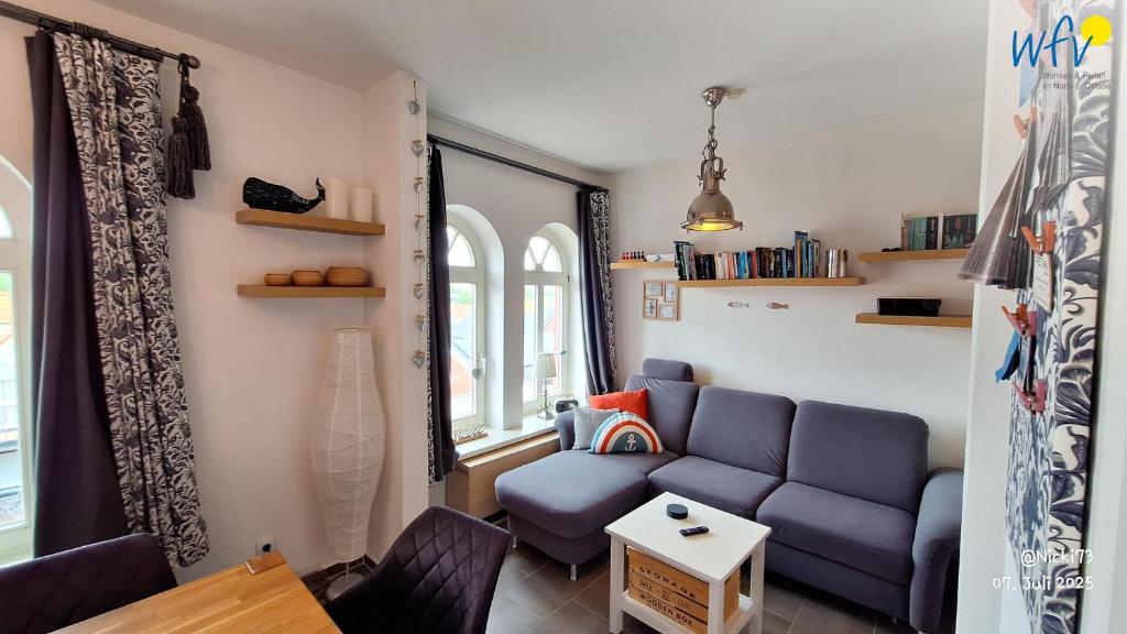 ein Wohnzimmer mit einem blauen Sofa und 2 Fenstern in der Unterkunft Haus Möwennest Ferienwohnung Kiek op de Toorns in Borkum