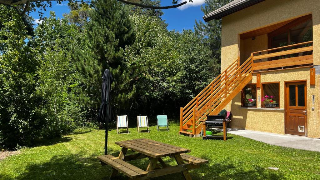 une table de pique-nique et des chaises dans l'herbe à côté d'une maison dans l'établissement Hébergement 4 étoiles Accès Pied des Pistes en Navette Gratuite, à Saint-Chaffrey