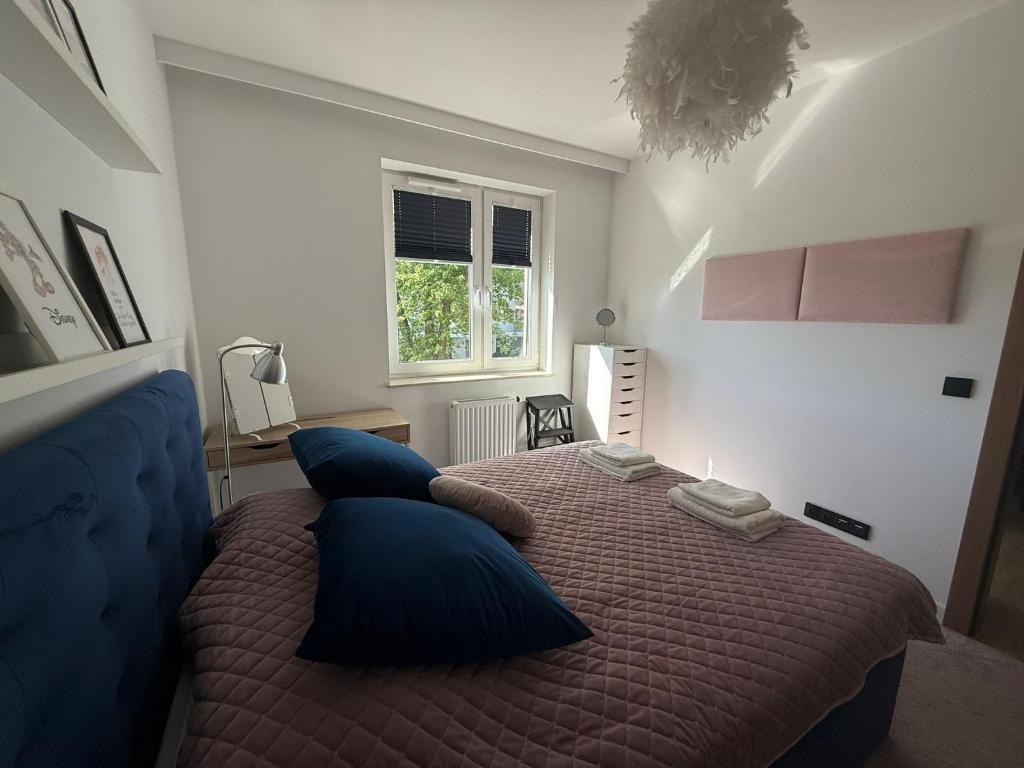 Un dormitorio con una cama con almohadas azules y una ventana. en Apartament Pod Areną, en Cracovia