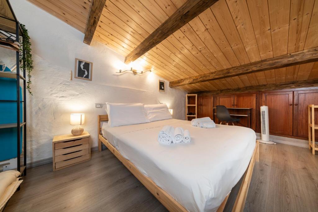 a bedroom with a large white bed with wooden ceilings at SASSARI-CENTRO Elegante Appartamento con WiFi e Netflix in Sassari