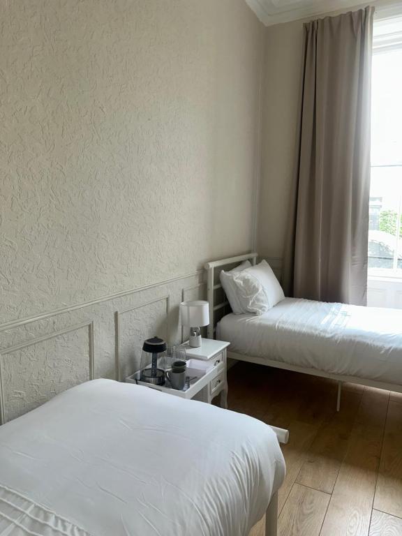 a hotel room with two beds and a window at Modern Twin Room In The Heart Of Edinburgh in Edinburgh