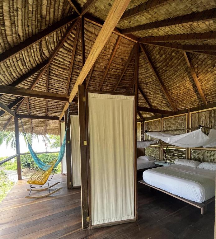 a bedroom with a bed and a hammock in a hut at Ecohotel Luzul in Nuquí