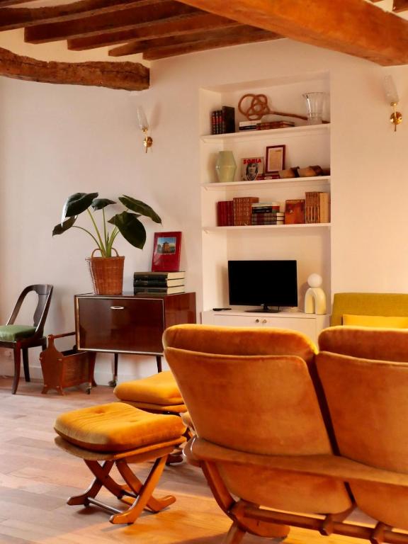 ein Wohnzimmer mit Stühlen und einem TV in der Unterkunft Ferme des Millonets - grand gîte in Vienne-en-Arthies