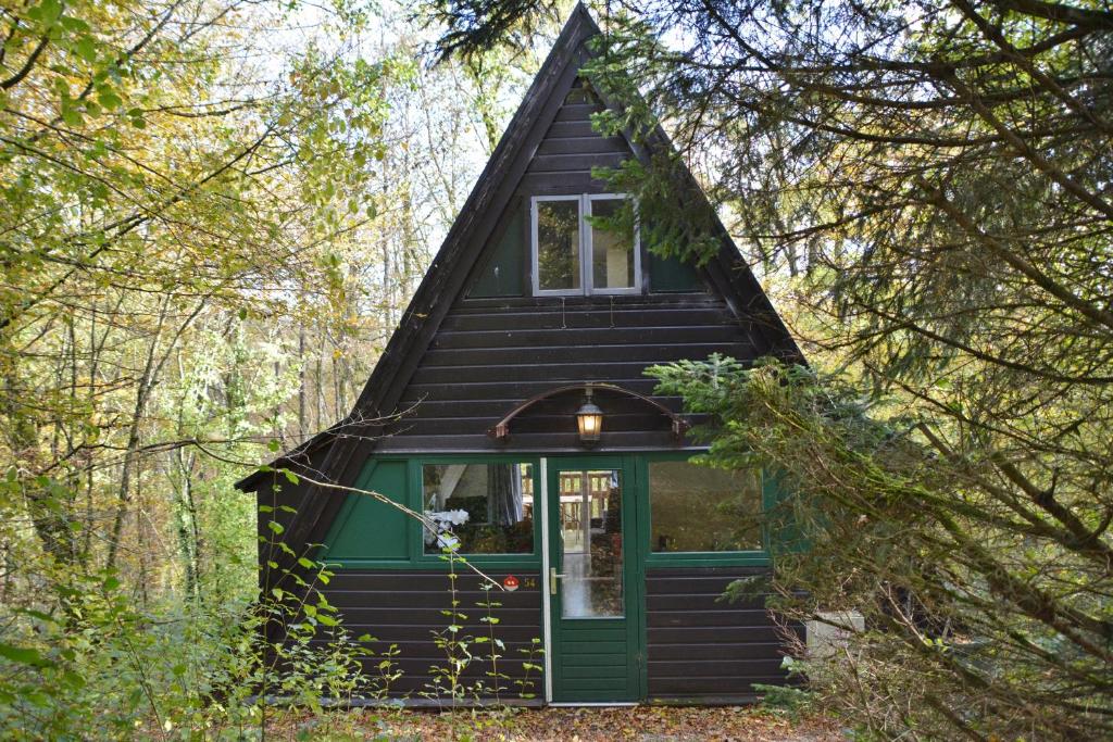 a black cabin with a green door in the woods at Villa Pimpelmees - Sunclass 54 in Durbuy