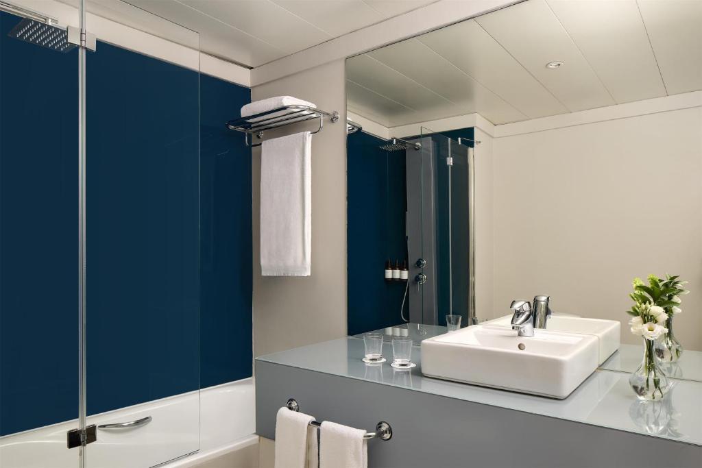 A contemporary bathroom with a vessel sink, mirrored wall and glass-screened tub.