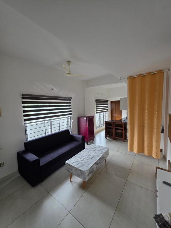 a living room with a black couch and a table at Atharva homes at Vallikavu Amritapuri in Perinād