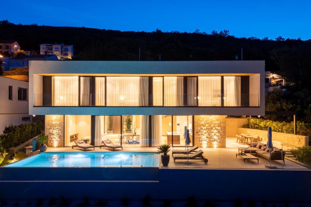 a house with a swimming pool at night at Opatija Luxury Villa Ella in Mošćenička Draga