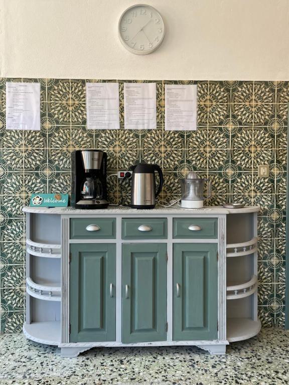 a green cabinet in a kitchen with a clock on the wall at Casa Valverde in Monsanto