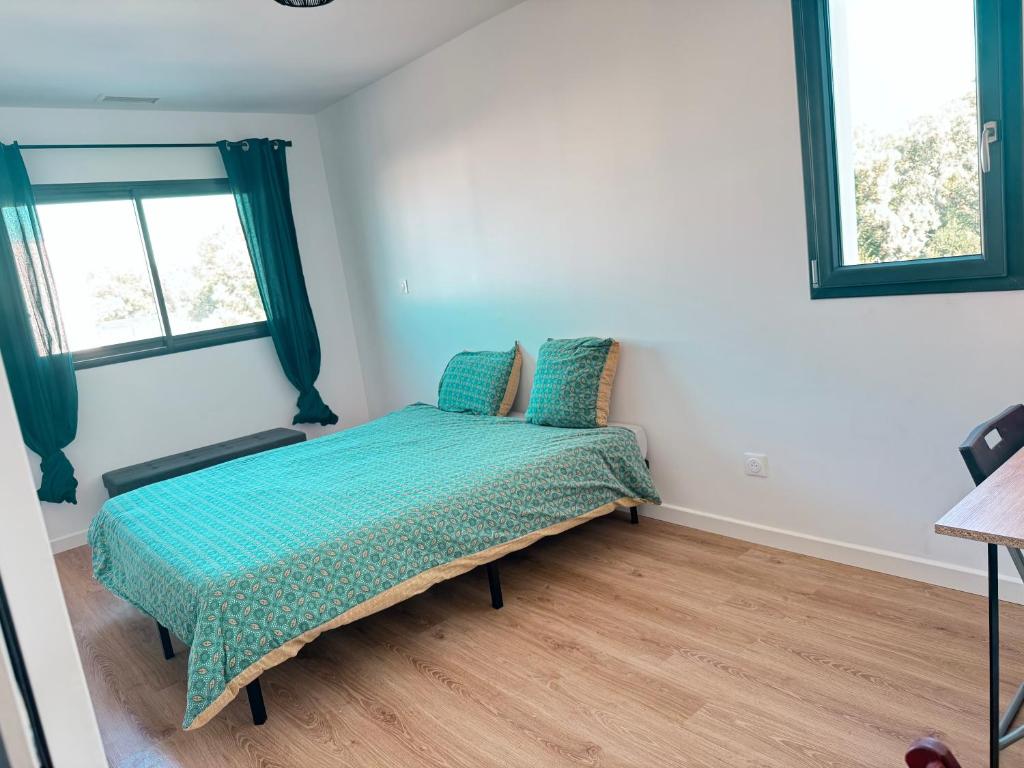 Un dormitorio con una cama con edredón verde y dos ventanas. en Chambre Privée Villa des Bananiers, en Baillargues