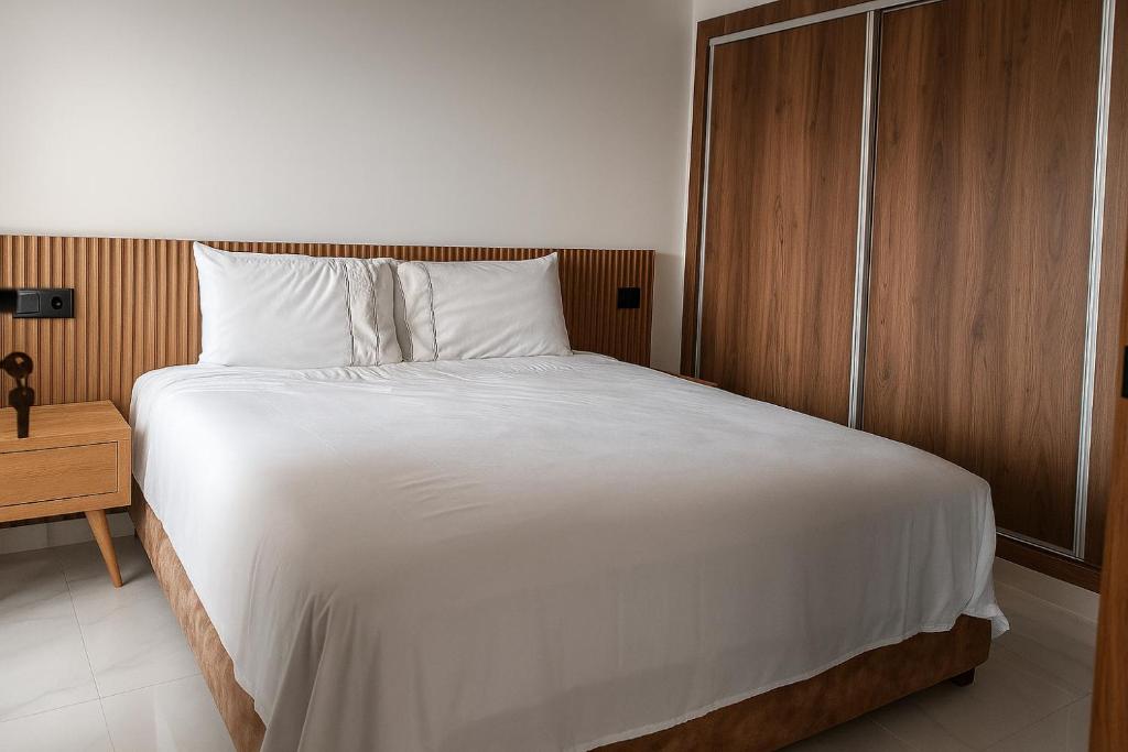 a bedroom with a large white bed and a wooden cabinet at Apartment - Mehdia Beach in Kenitra