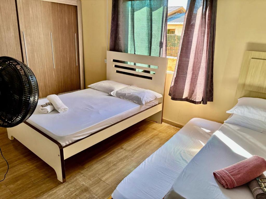 a small bedroom with two beds and a fan at Casa próxima ao shopping Lages e a festa do pinhão in Lages