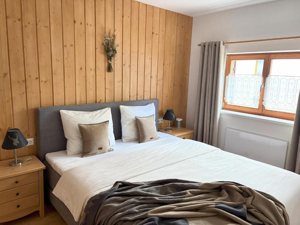 a bedroom with a large white bed with wooden walls at Alpen family apartment Bergfreunde near skilift and golf course in Bad Kleinkirchheim