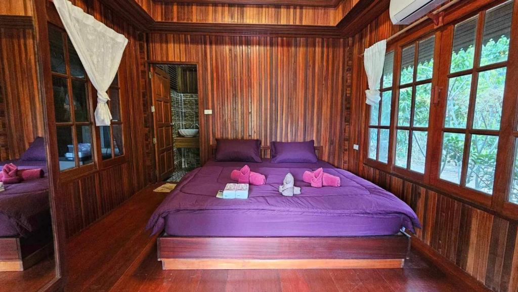 a bedroom with a purple bed with pink pillows at Thai Home Resort in Phra Ae beach