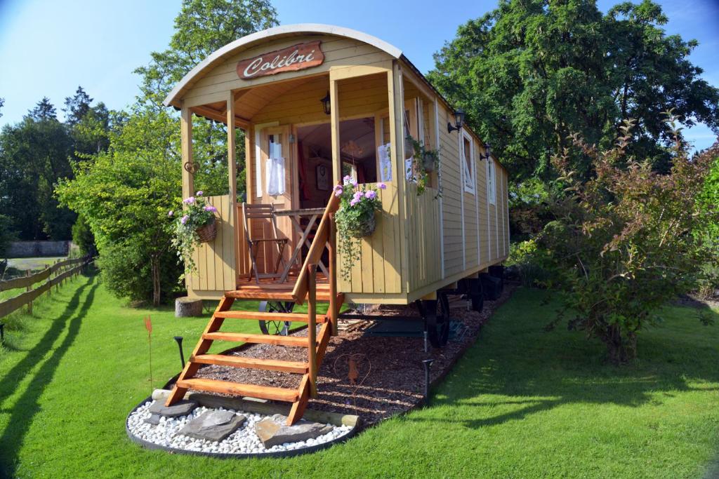 a train cabin with a staircase in a yard at Insolites à Chimay - Les roulottes à Rièzes in Chimay