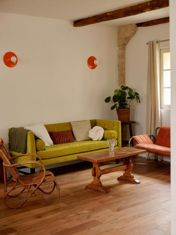 ein Wohnzimmer mit einem grünen Sofa und einem Couchtisch in der Unterkunft Ferme des Millonets - petit gîte in Vienne-en-Arthies