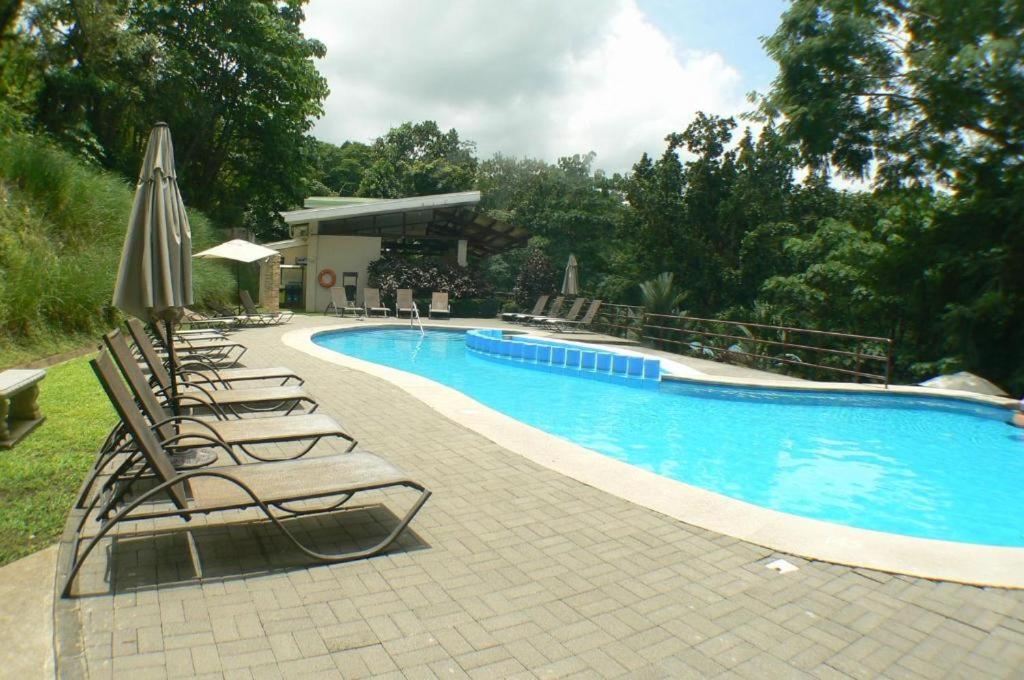 una piscina con tumbonas y sombrilla en Sunny Home Herradura - Family & Work From Beach, en Herradura