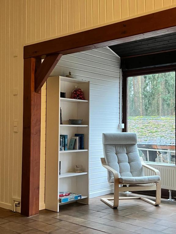 a chair sitting in a room with a book shelf at Taylors Allerhaus in Hornbostel